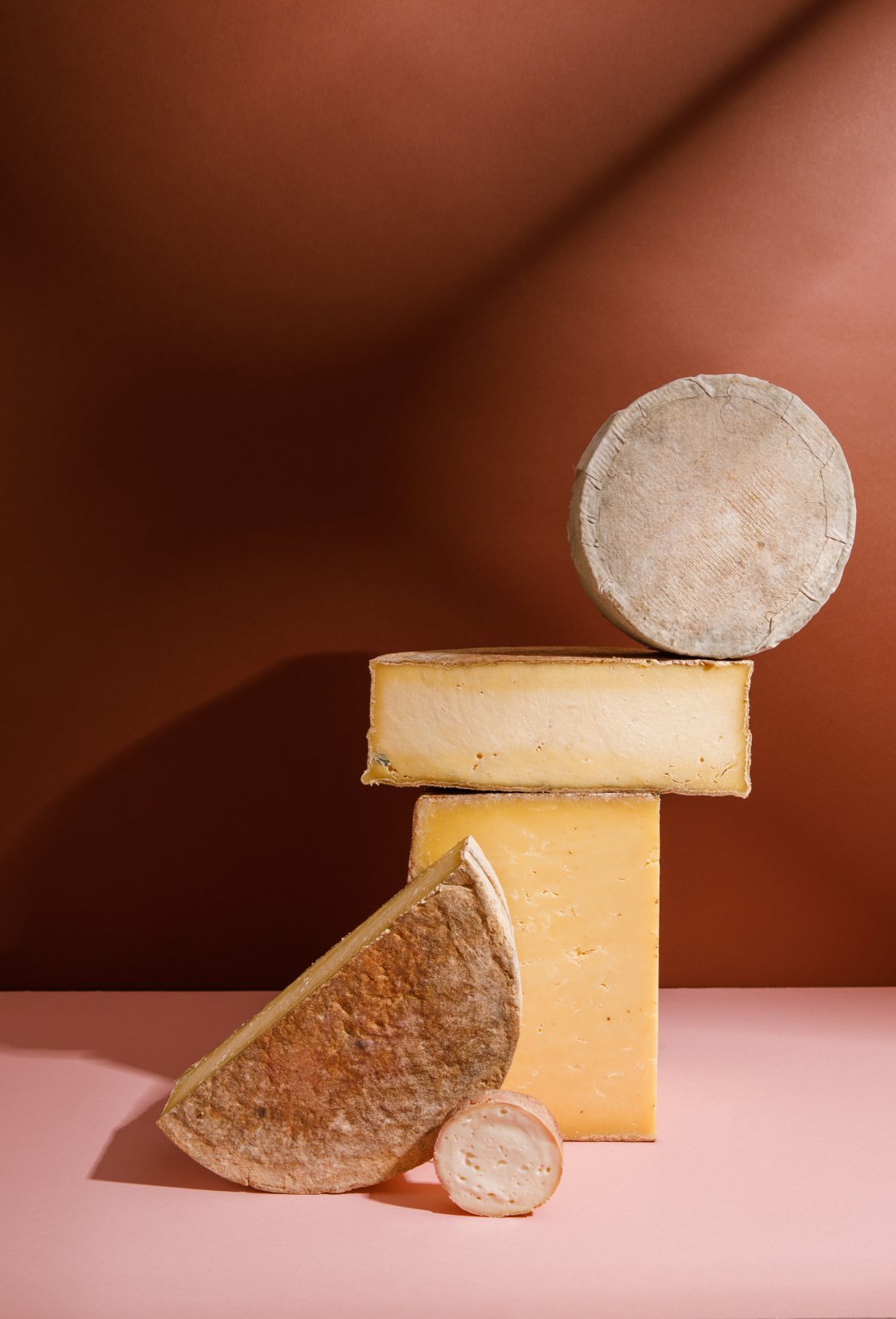 photograph of an abstract sculpture made from cheese. 4 large pieces of cheese are stacked to form an off centre tower