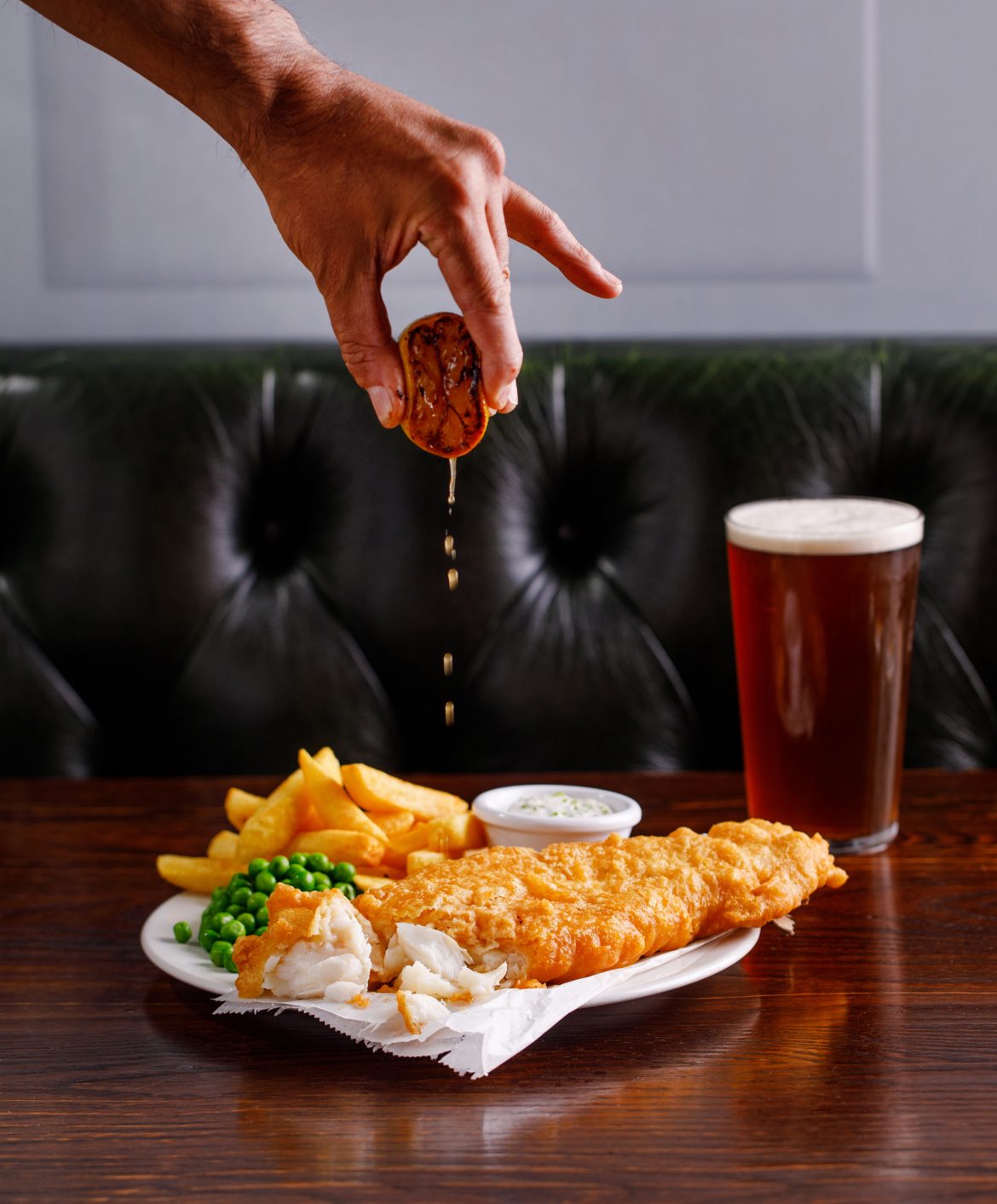 photo of fish and chips with lemon being squeezed over the top