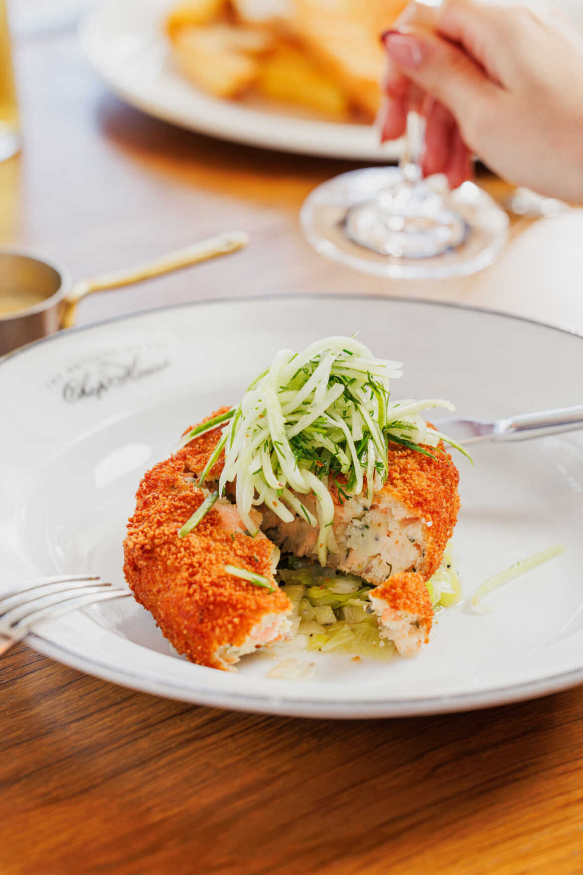 A plate of food on a table, a fishcake being cut open to show the inside of the fishcake