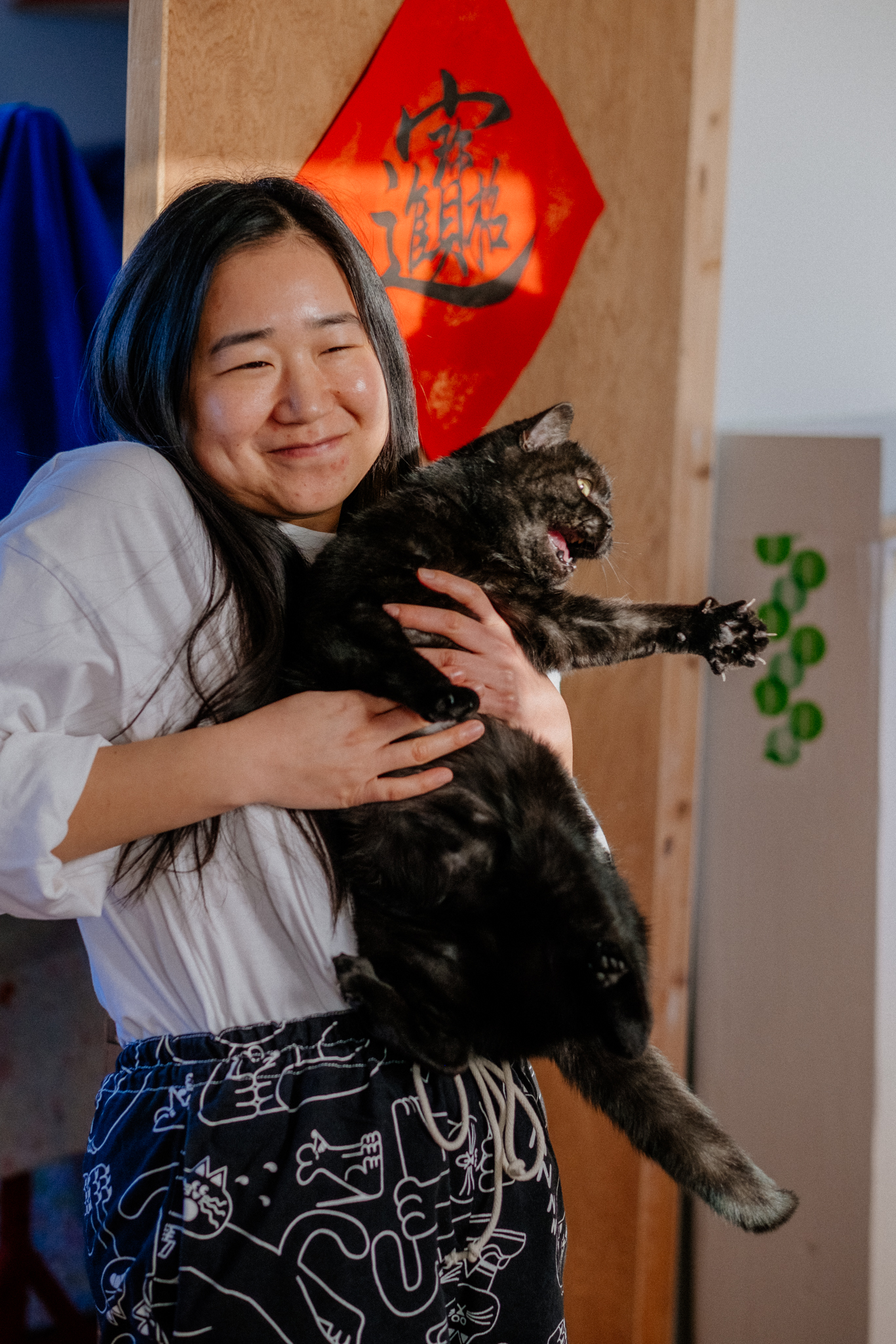 photograph of a woman holding a black cat and the cat is very unhappy