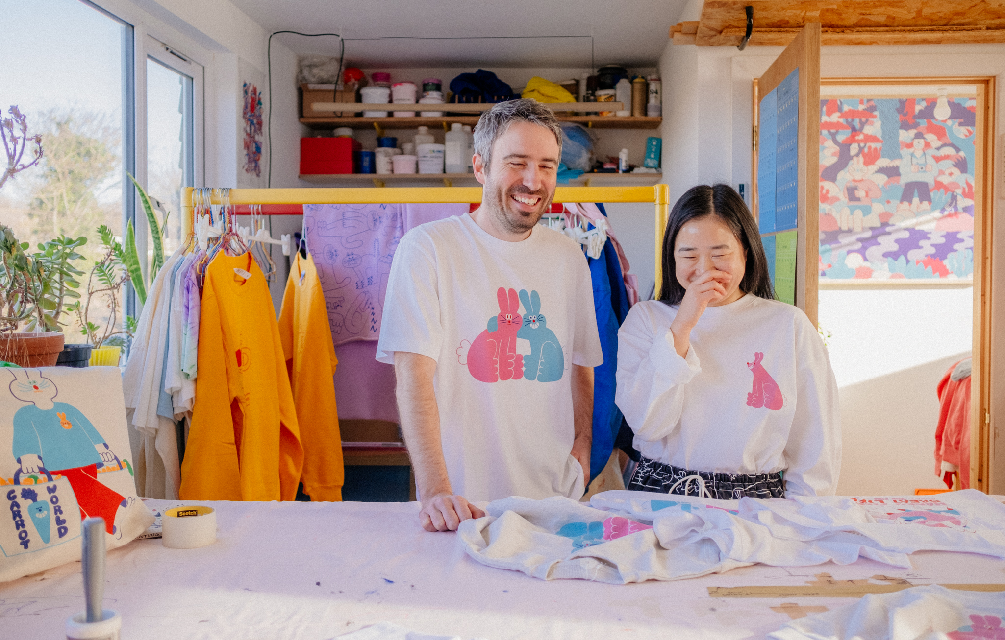 photograph of two artists wearing their own designs on t-shirts in their home studio