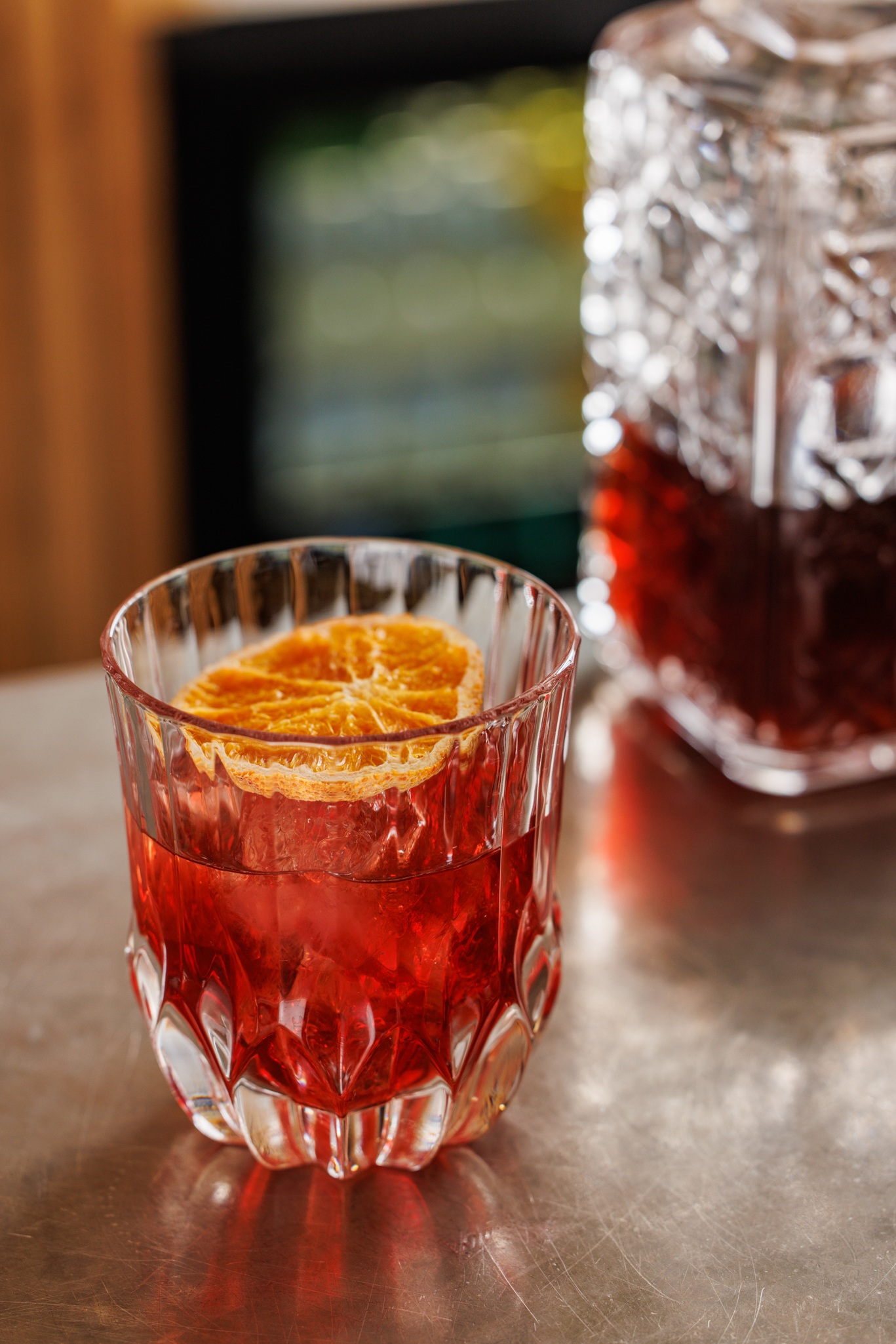 Close-up of a vibrant Negroni cocktail with orange slice garnish in a cut-glass tumbler at the bar of The Mount gastropub.