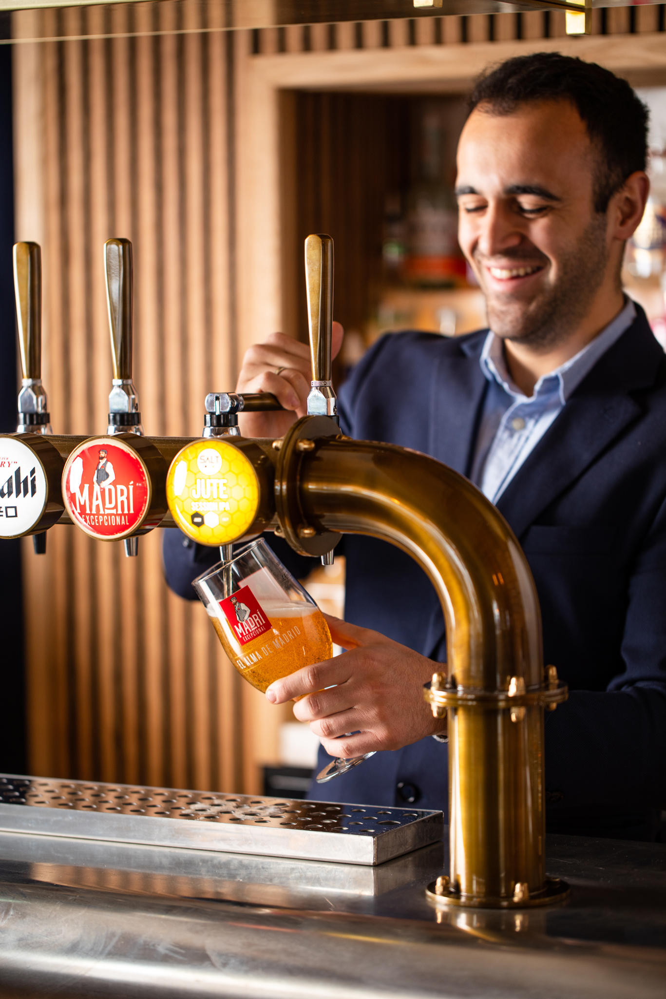Bartender pouring a pint of Madri beer from the tap behind the bar at The Mount, showcasing the pub’s drink offerings.