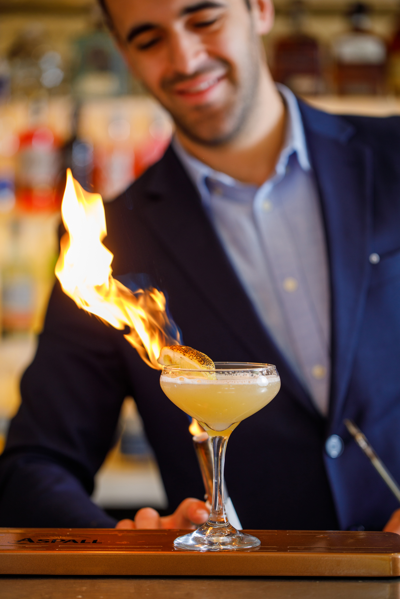 Bartender presenting a flaming cocktail with a torched garnish, capturing a dramatic drinks moment at The Mount restaurant bar.